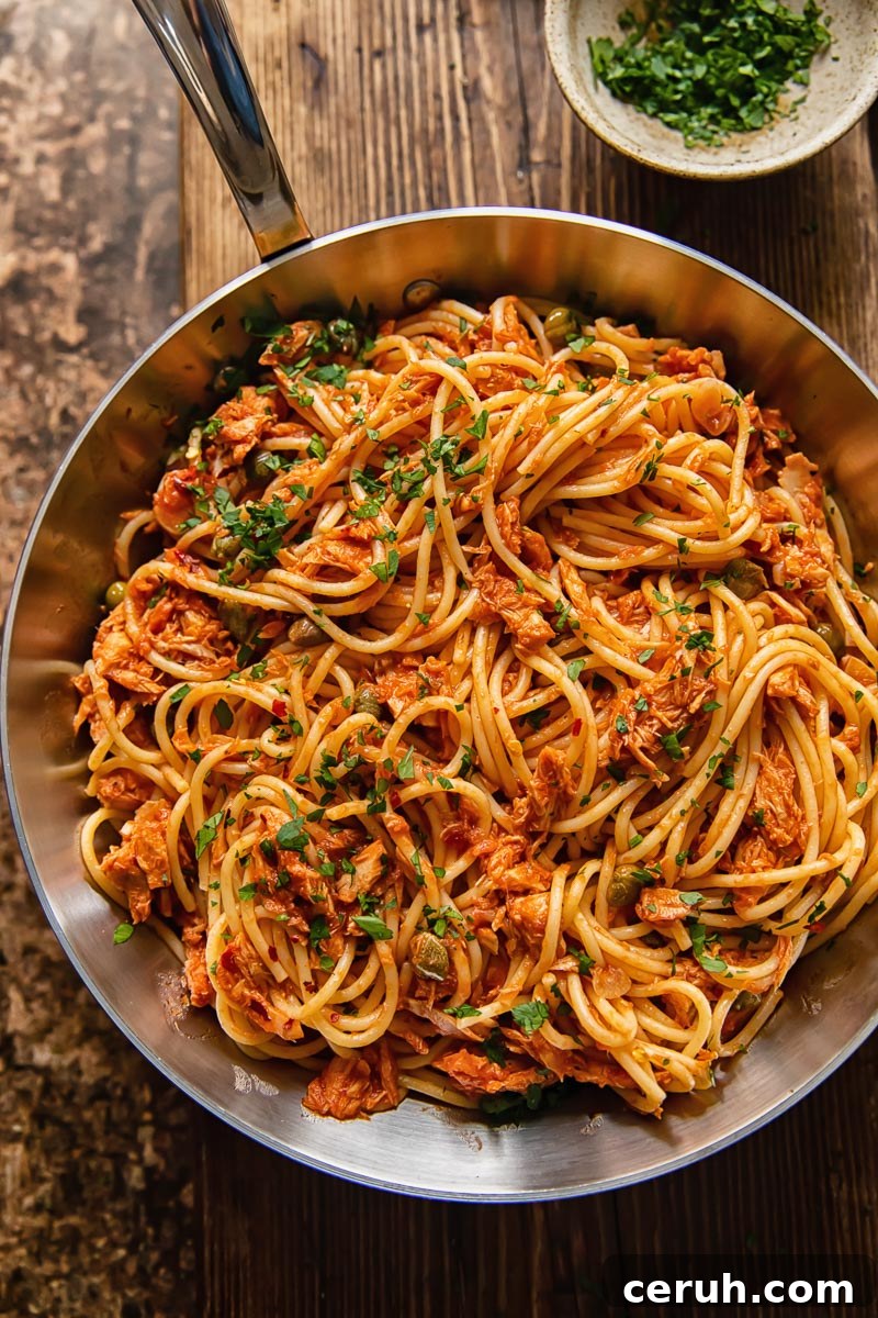 15-Minute Tuna Pasta with Capers and Lemon Zest 3 top dow view of tuna pasta in a tomato sauce in a pan on dark wood background