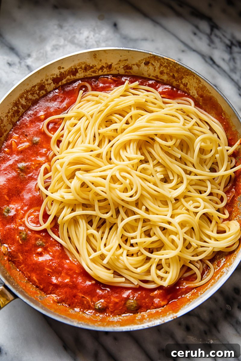 15-Minute Tuna Pasta with Capers and Lemon Zest 4 spaghetti on top of red sauce in a pan
