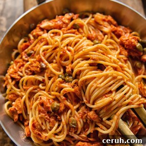 15-Minute Tuna Pasta with Capers and Lemon Zest 7 top down view of spaghetti in red sauce in a pan