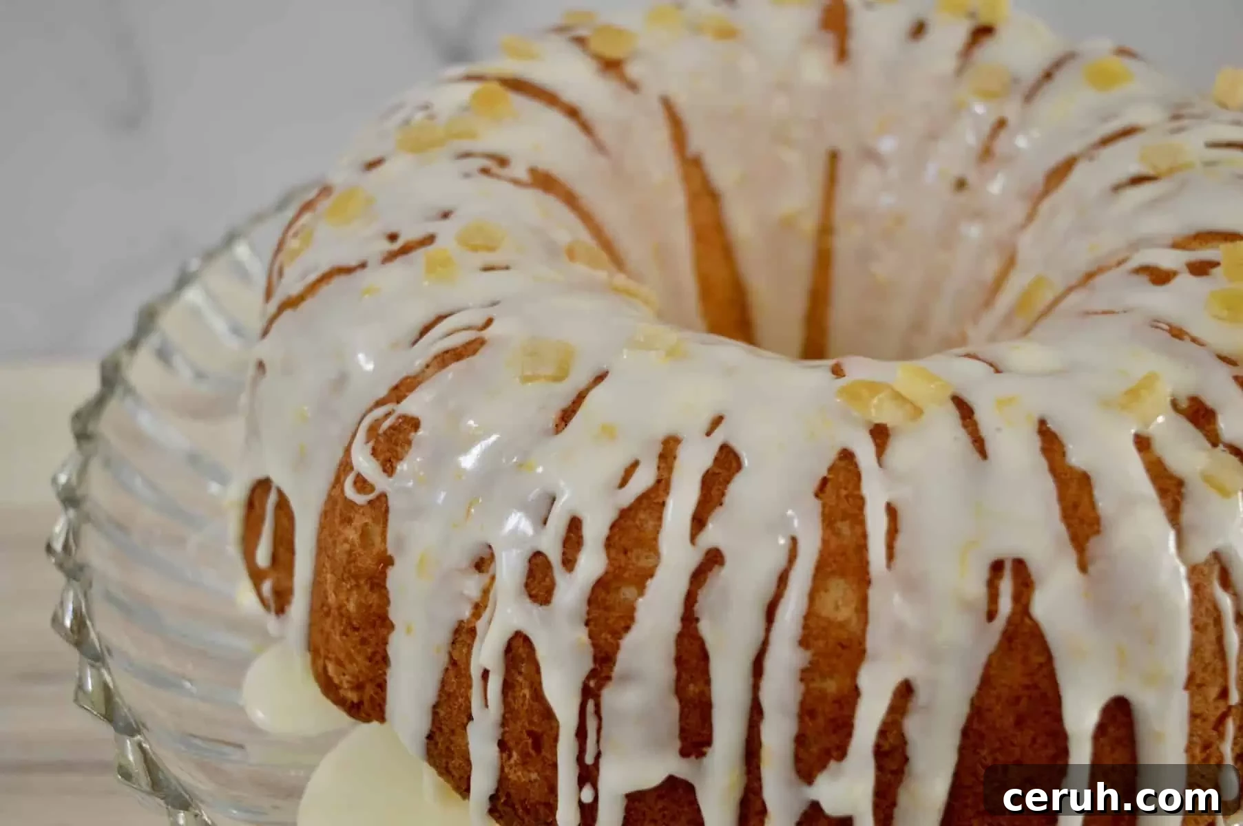 Italian bundt cake on a glass pedestal with drizzle and candied citrus peel on it. 