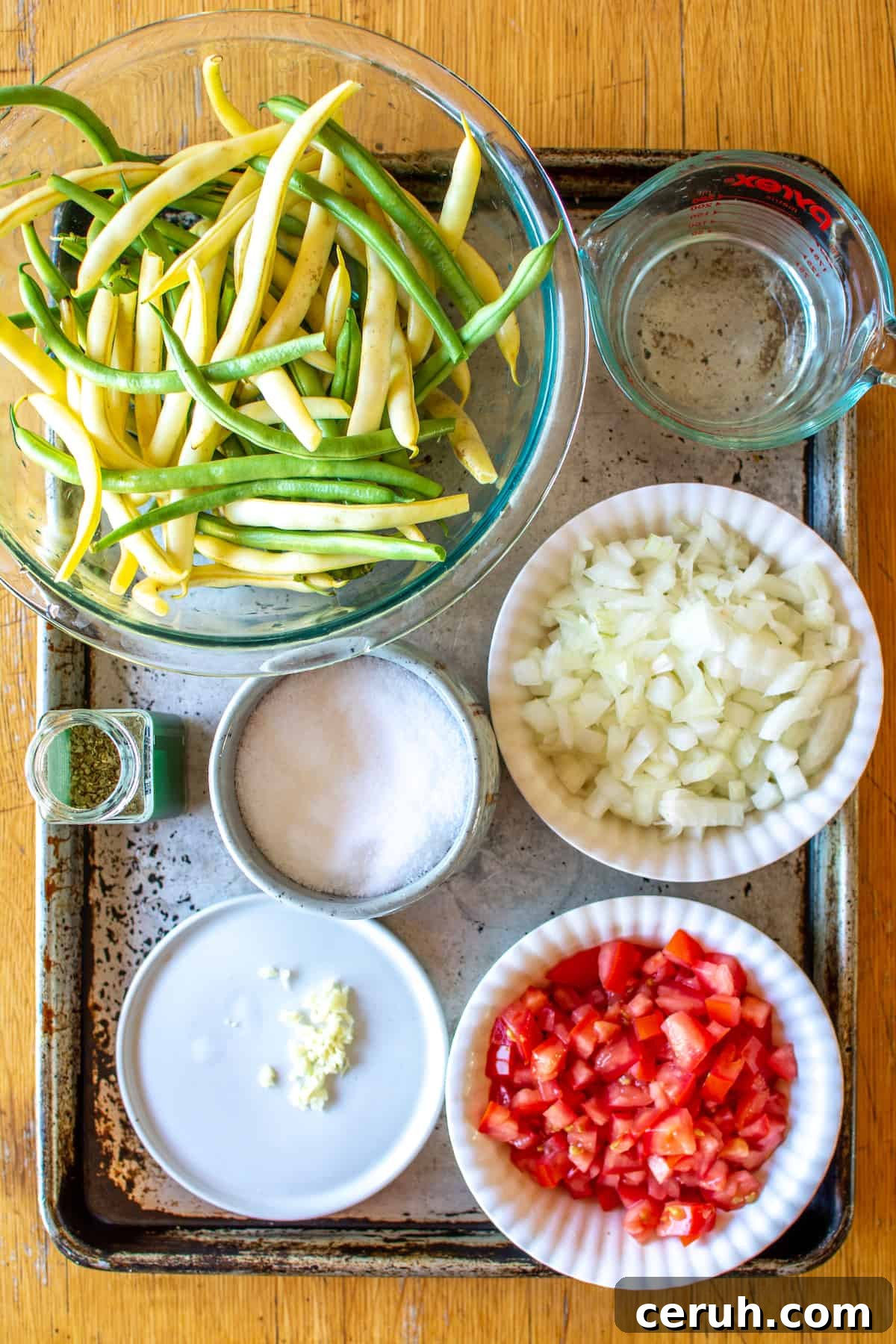 All the ingredients to make stewed green beans including green beans, yellow wax beans, water, onions, tomatoes and more.