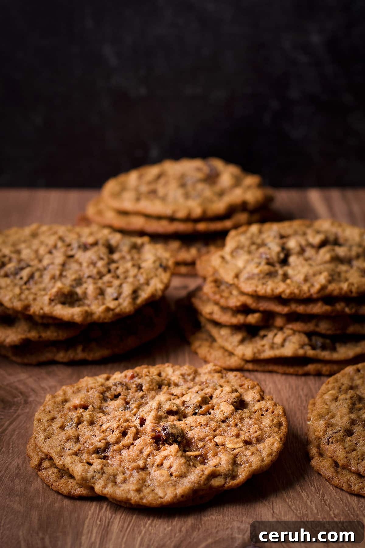 Several stacks of homemade classic thin and chewy oatmeal raisin cookies.
