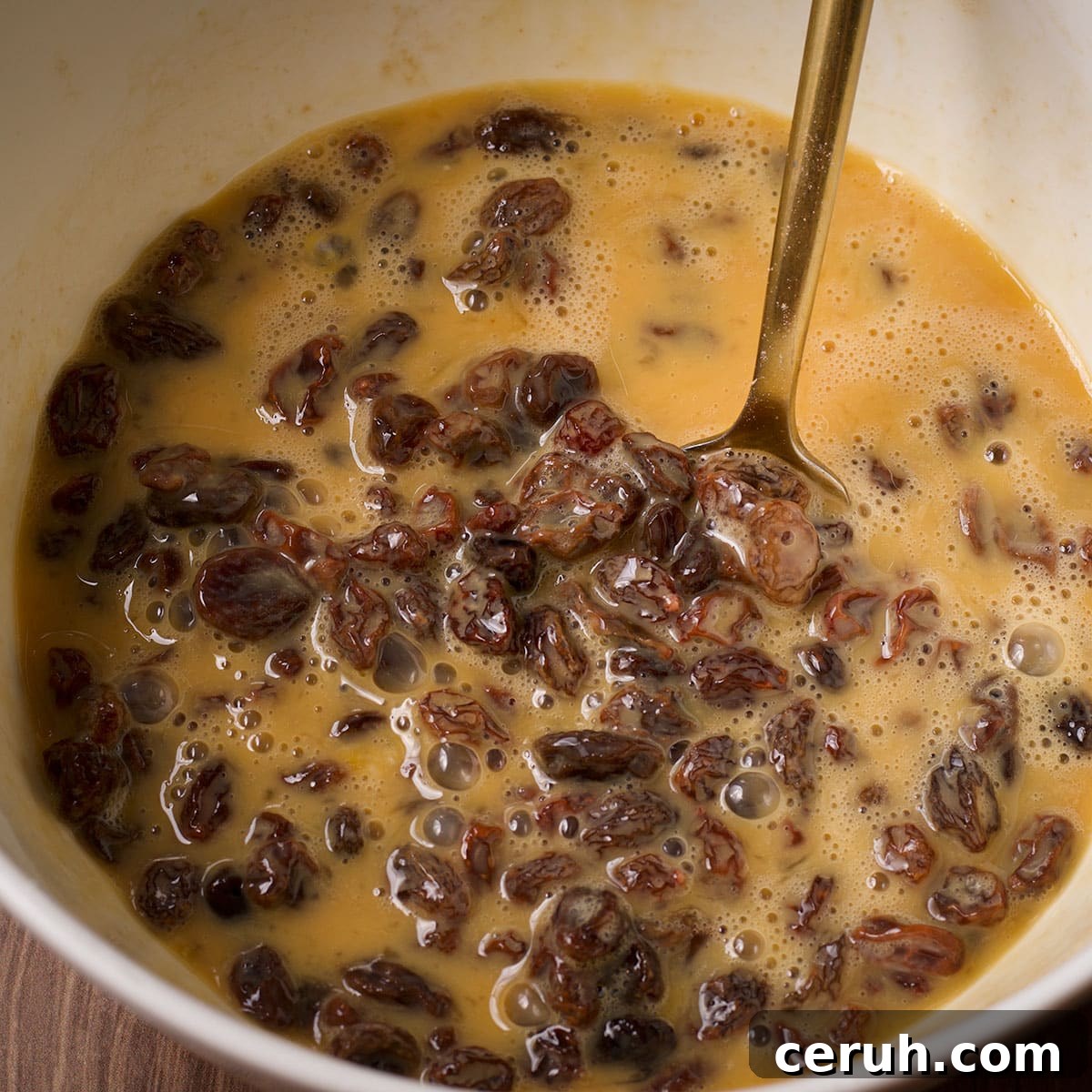 Raisins soaking in beaten eggs, vanilla, and almond extract.