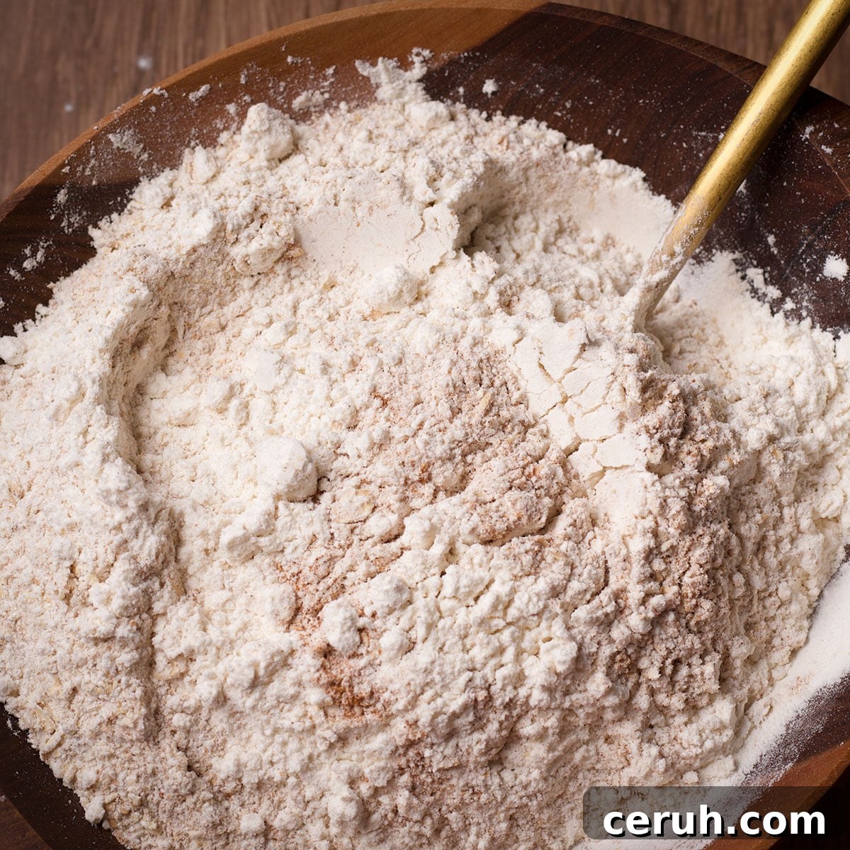 Using a spoon to stir whole wheat flour, all-purpose flour, baking soda, and salt together in a bowl.