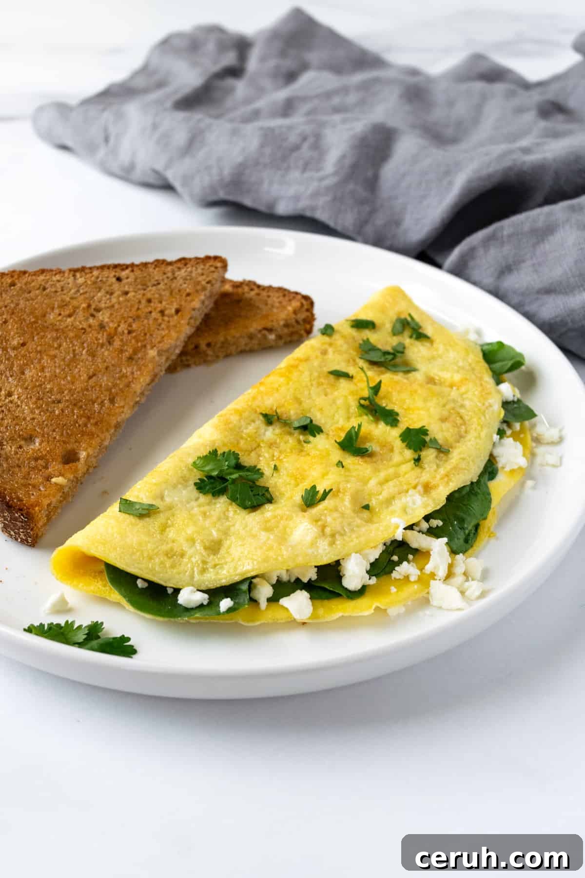 Spinach and Feta Omelet on a white plate with wheat toast.