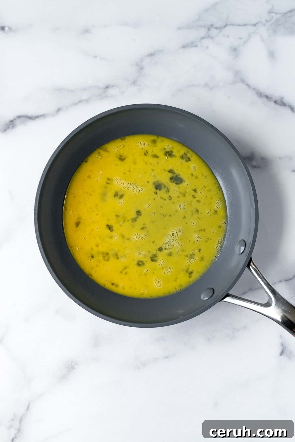 Whisked eggs in a small frying pan.