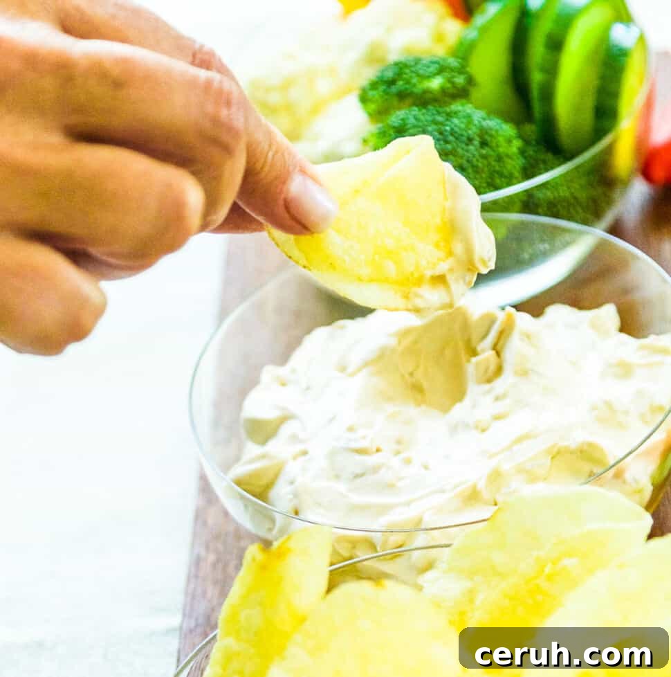 A lady dipping a potato chip into onion dip.