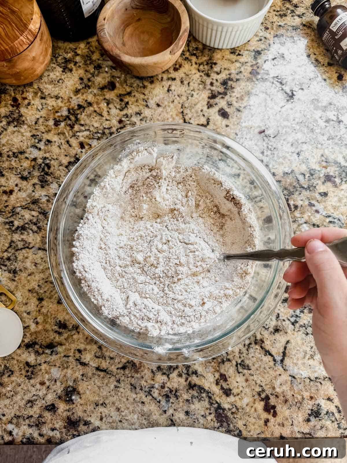 whisking dry ingredients for gingerbread latte cookies in a glass bowl.