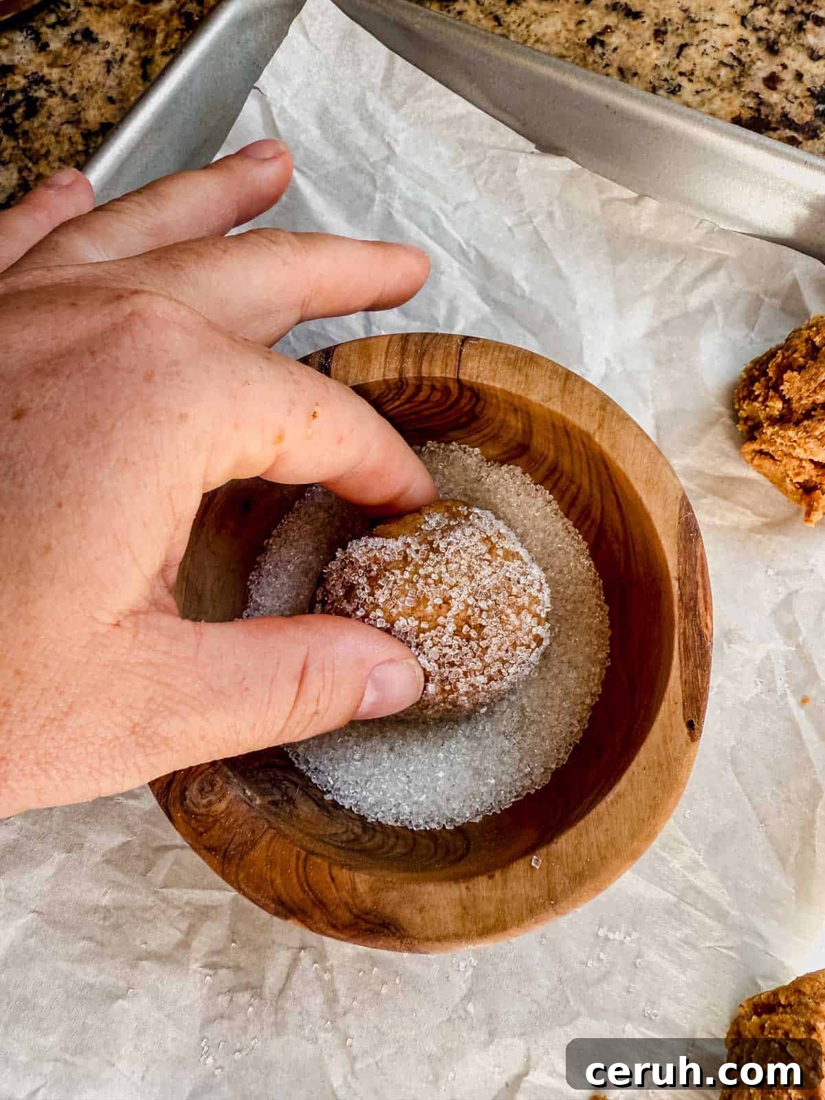 rolling gingerbread latte cookie dough ball in a bowl of sugar.
