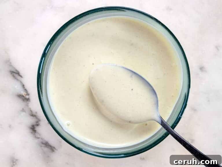 Classic Creamy Coleslaw Recipe for BBQs and Weeknight Meals 13 Coleslaw dressing with a black spoon
