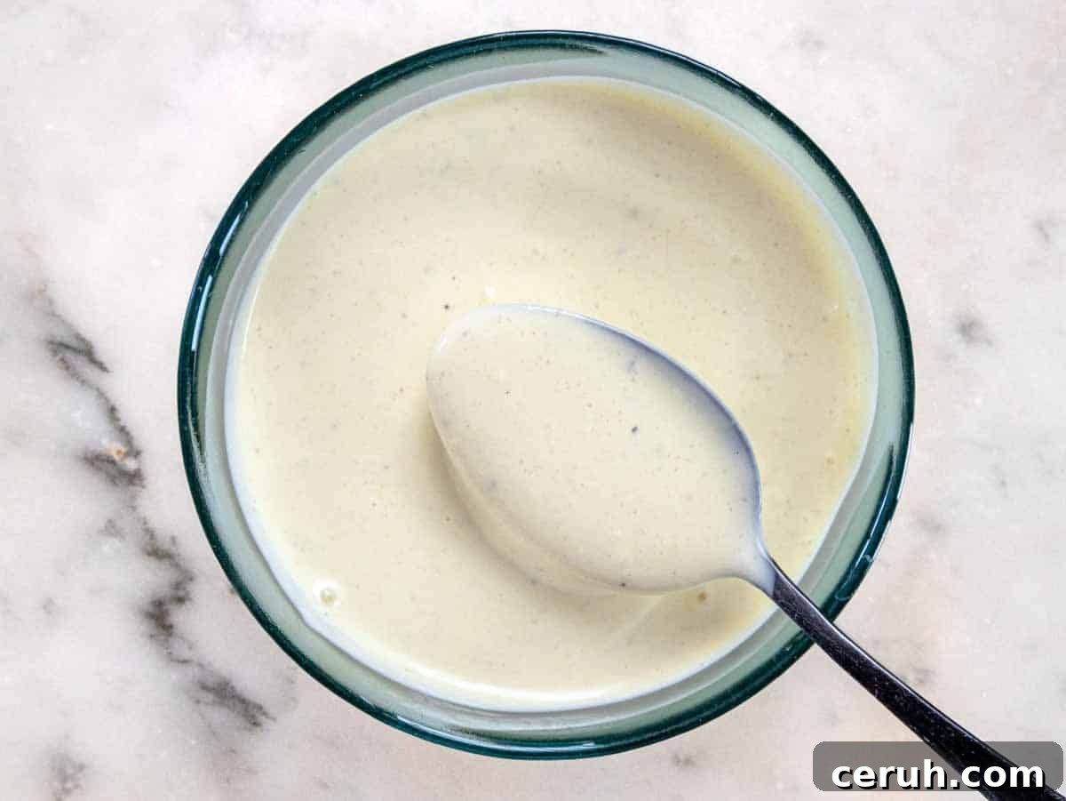 Classic Creamy Coleslaw Recipe for BBQs and Weeknight Meals 8 Coleslaw dressing with a black spoon