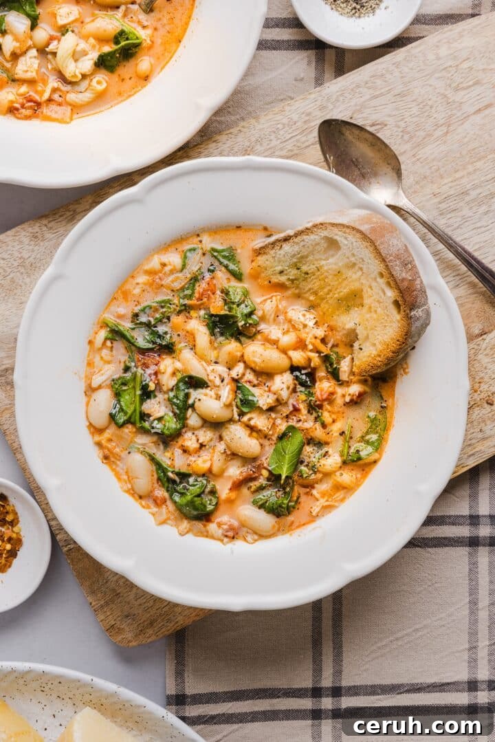 Marry me chicken soup in a scalloped white bowl with crusty bread dipped in.