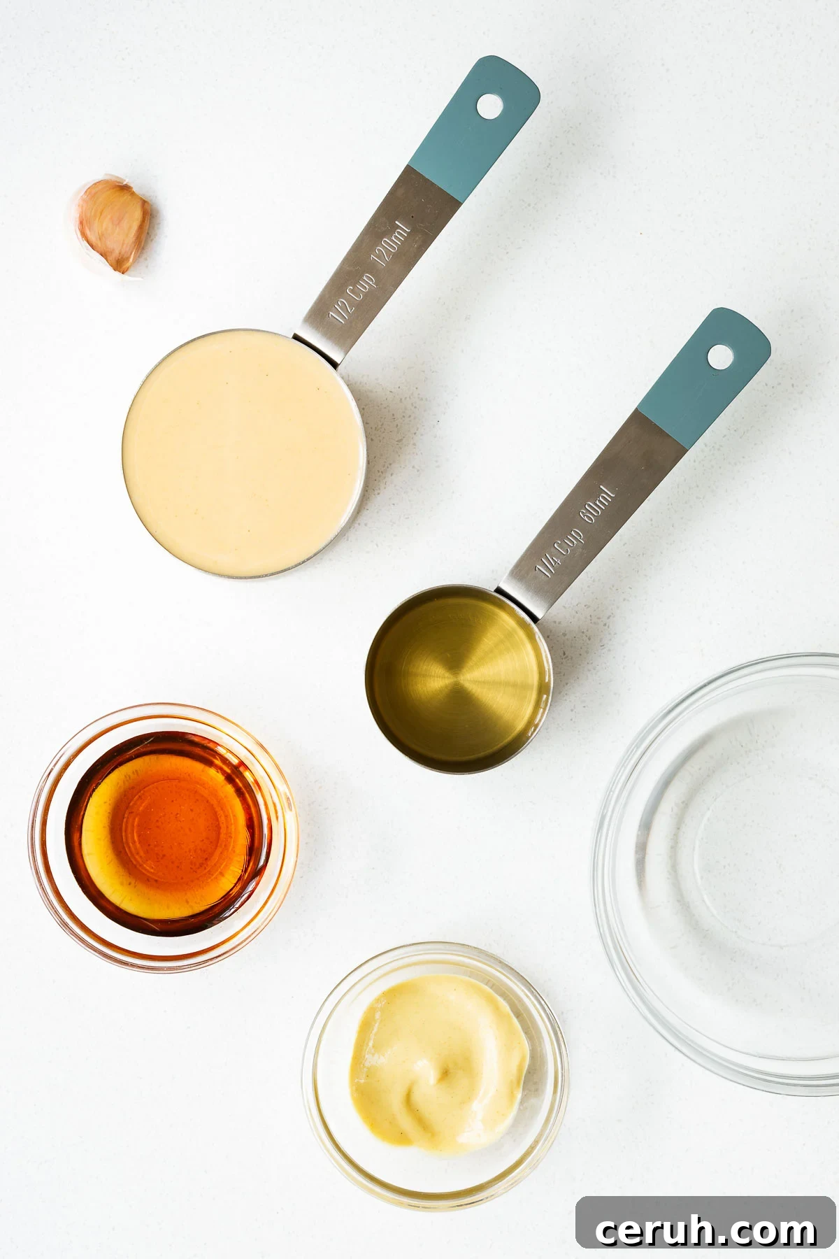 Vegan tahini dressing with maple syrup and dijon mustard ingredients arranged on a kitchen counter viewed from above.