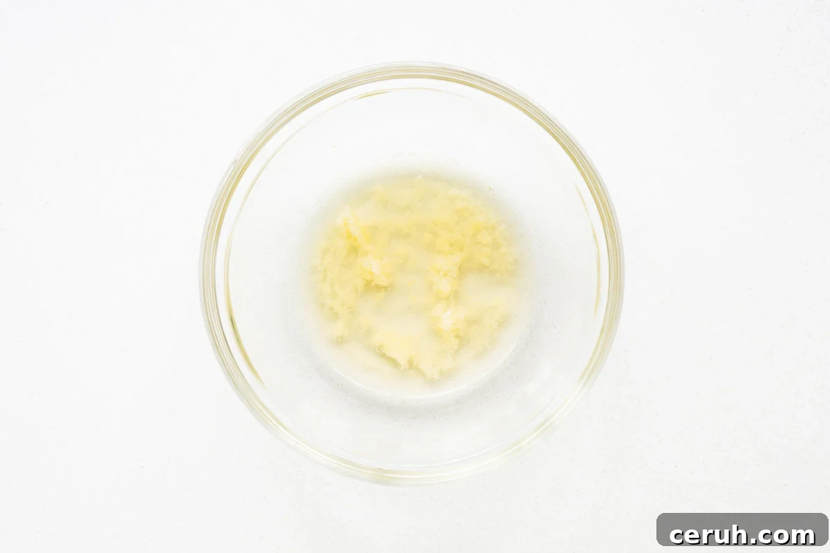 Grated garlic in a bowl with apple cider vinegar viewed from above.