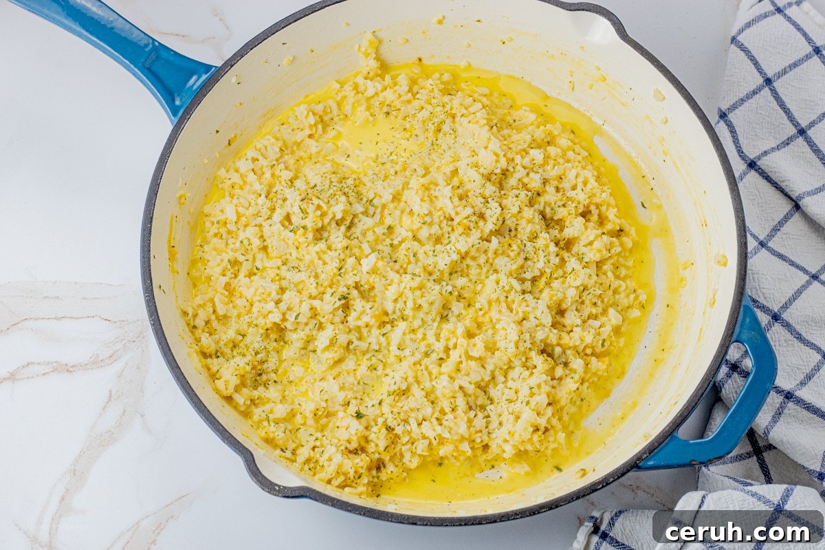 cauliflower rice in a cheesy sauce in a large skillet