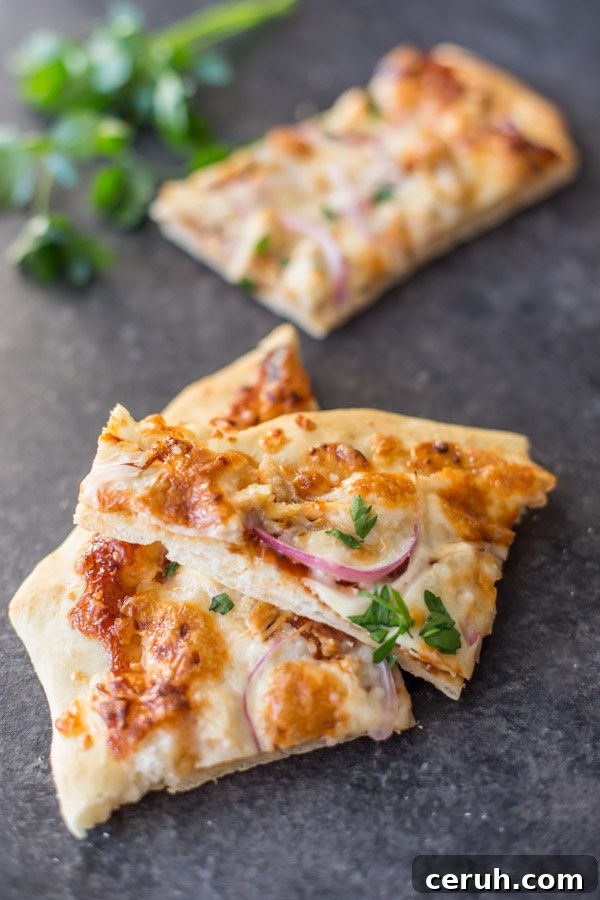 Two slices of Barbeque Chicken Pizza, with another slice in the the background next to some flat leaf parsley.
