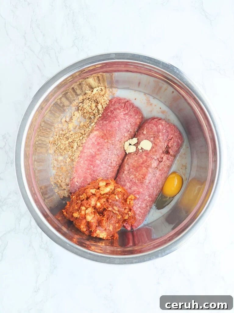 Meatloaf ingredients unmixed in a metal mixing bowl.