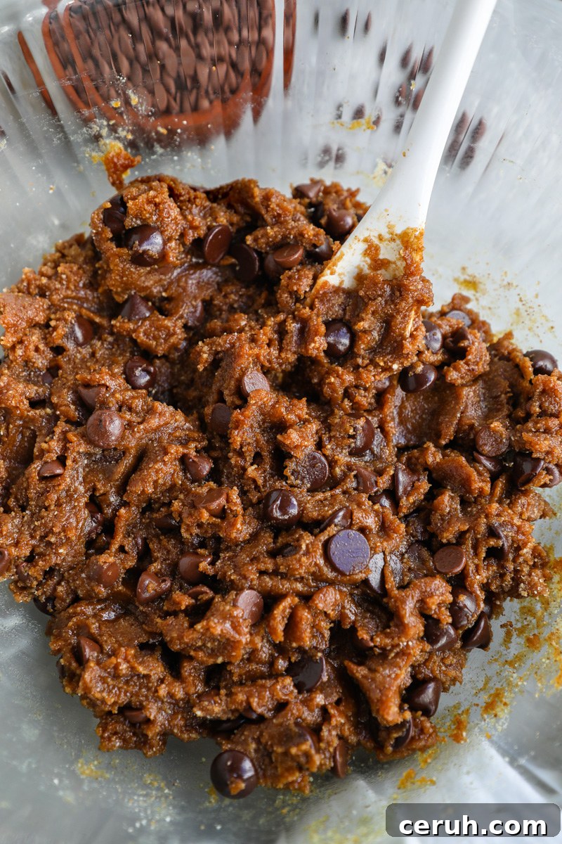 A large clear mixing bowl with with almond butter chocolate chip cookie dough