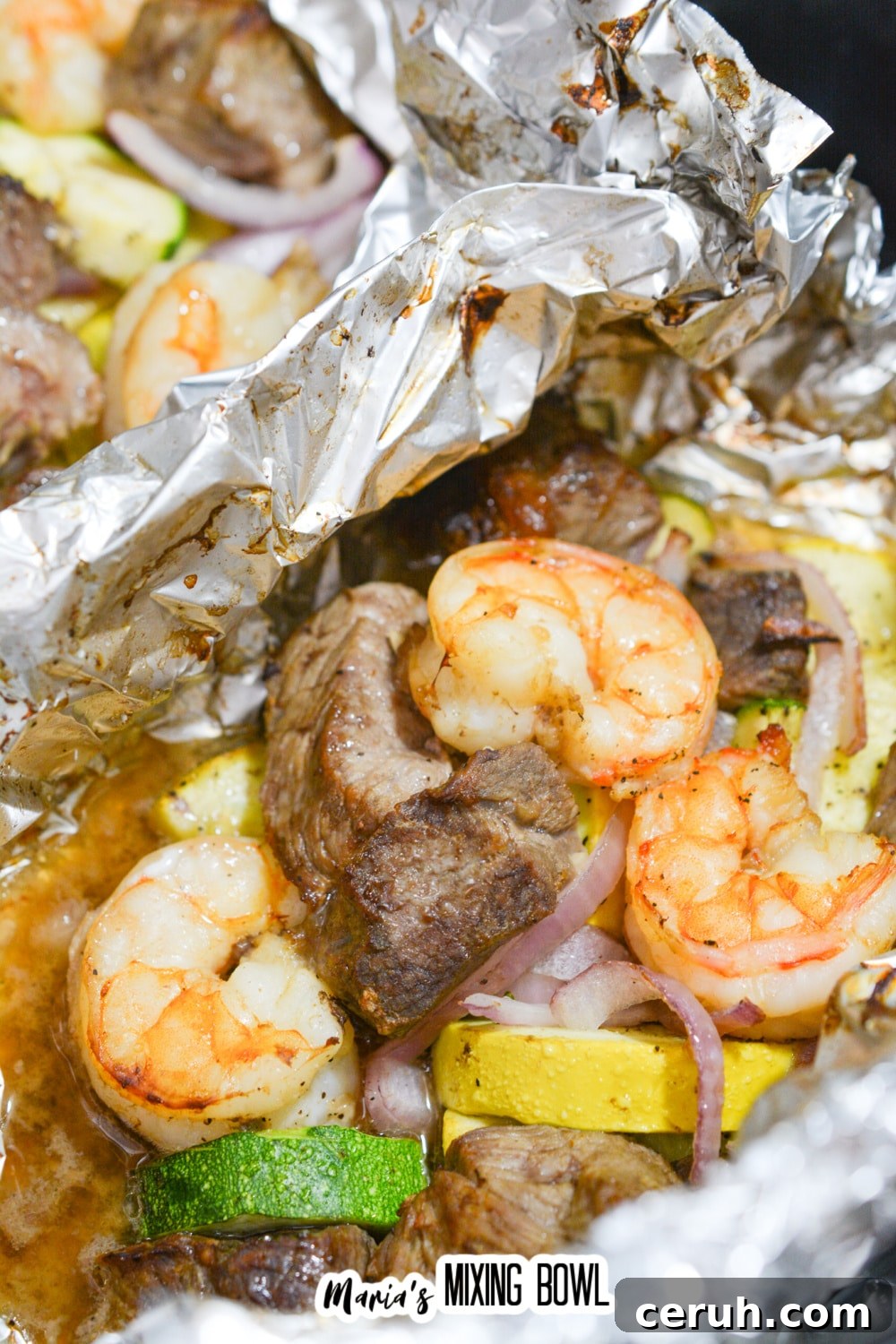 close up of the inside of a foil packet filled with steak and shrimp.