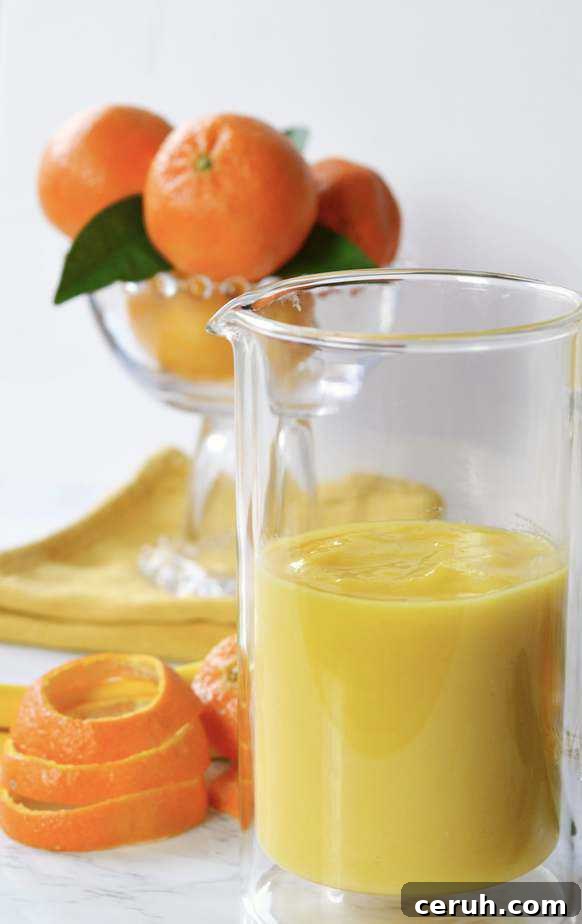 pitcher full of orange mango freeze with bowl of tangerines.