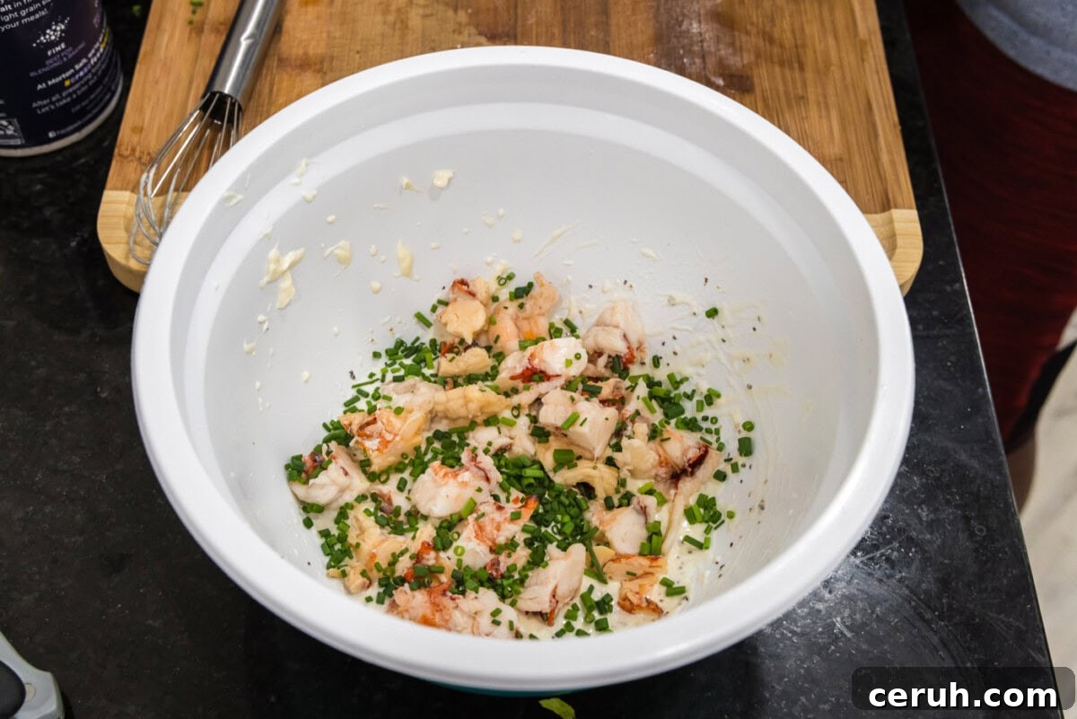chopped chives added to cooked lobster meat and dressing in a bowl