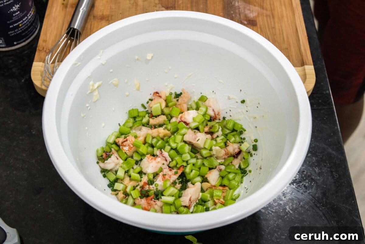 diced celery added to lobster and dressing in a bowl