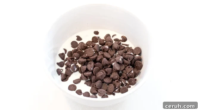 Semi sweet chocolate chips and heavy cream in a white bowl