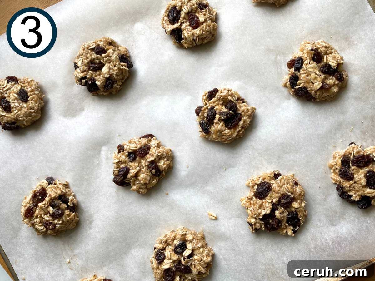Uncooked banana oatmeal raisin cookies on a parchment-lined cookie sheet.