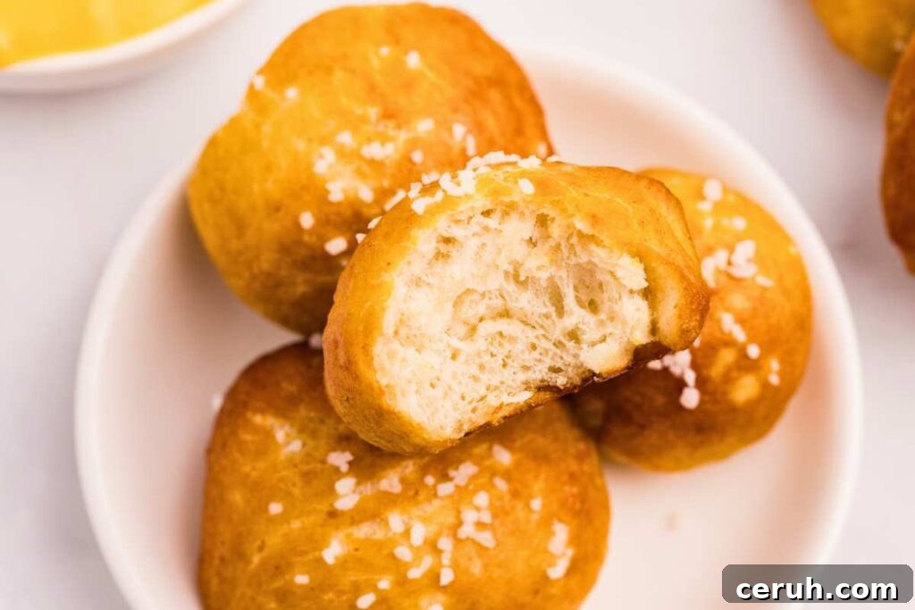 four pretzel bites in a bowl, with a bite taken out of one.