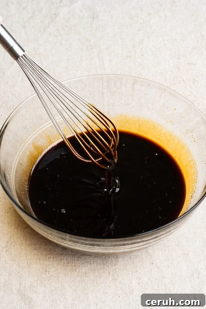 A wire whisk mixing molasses and coffee together in a bowl.