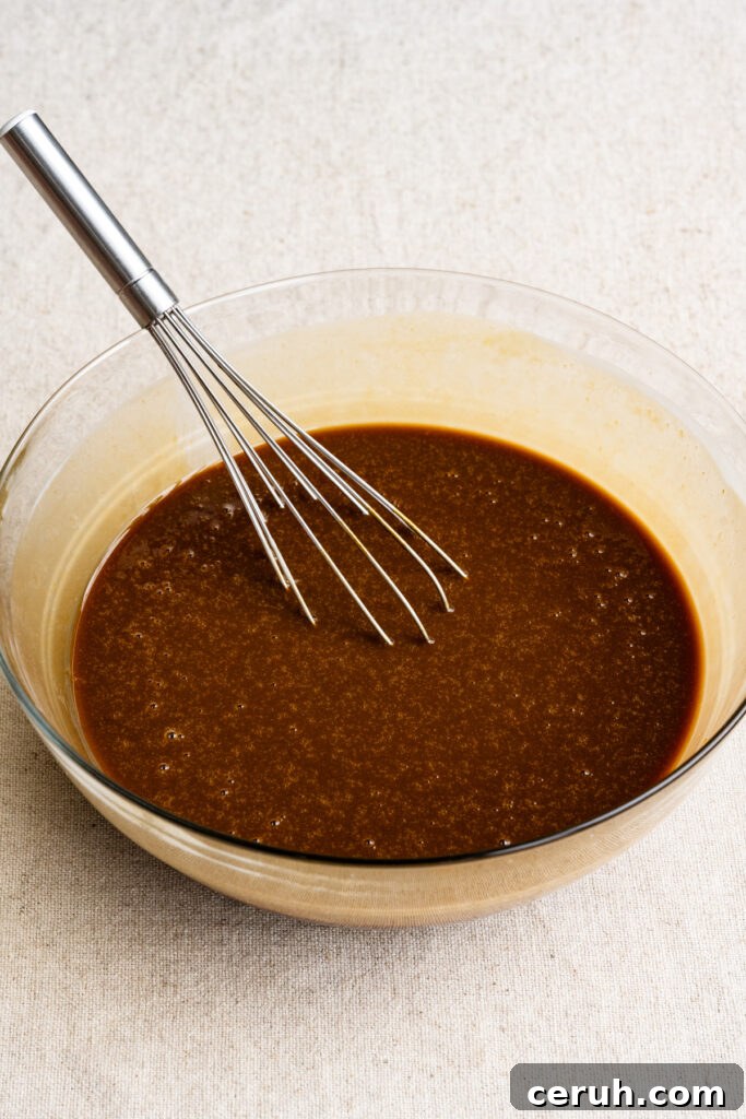 Liquid cake ingredients in a mixing bowl with a whisk.