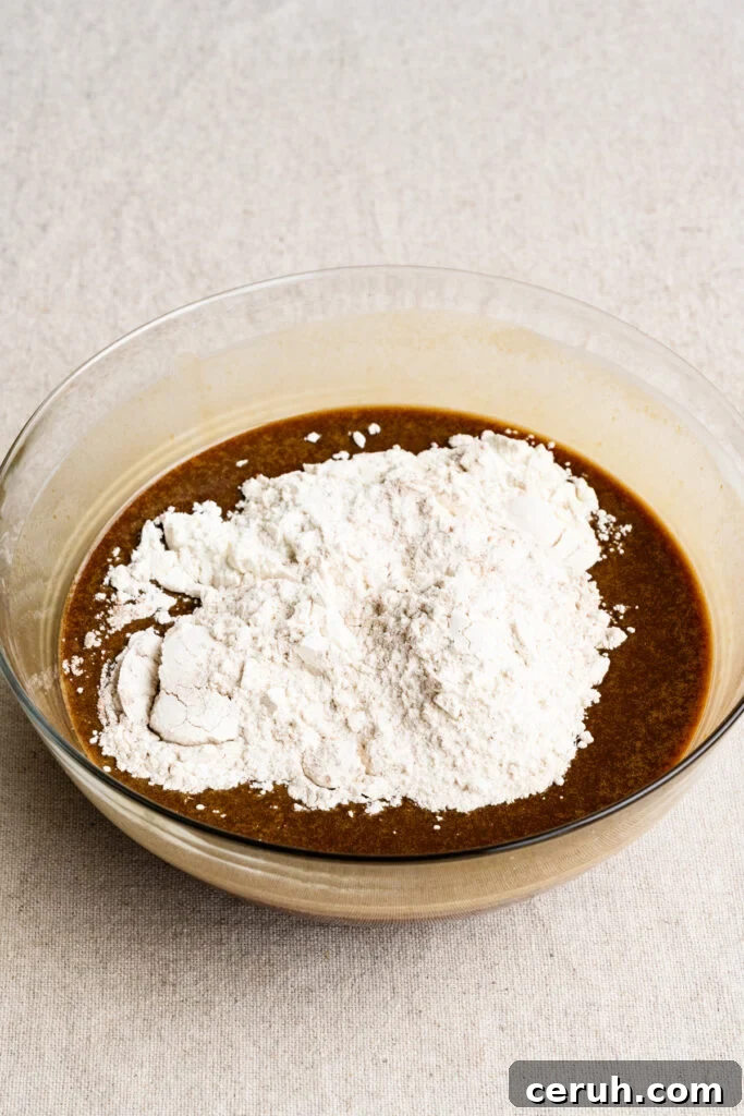 Flour on top of liquid cake batter in a bowl.