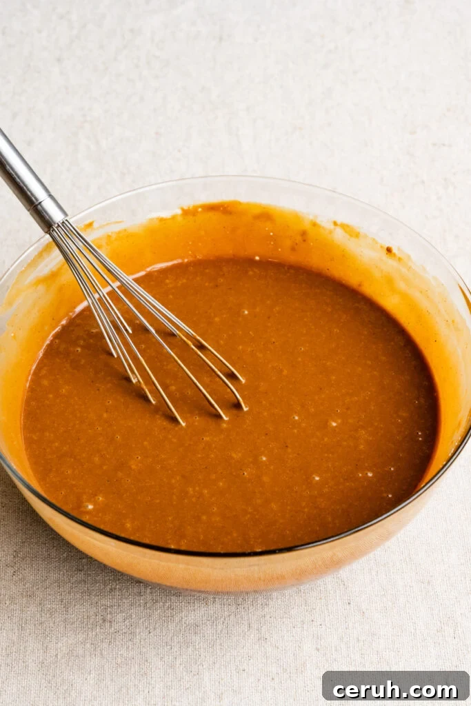 Gingerbread cake batter in a mixing bowl with a whisk.