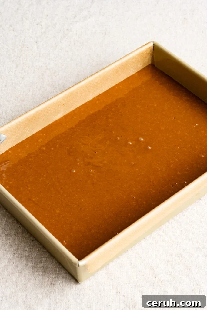 Rectangular baking pan filled with gingerbread cake batter.