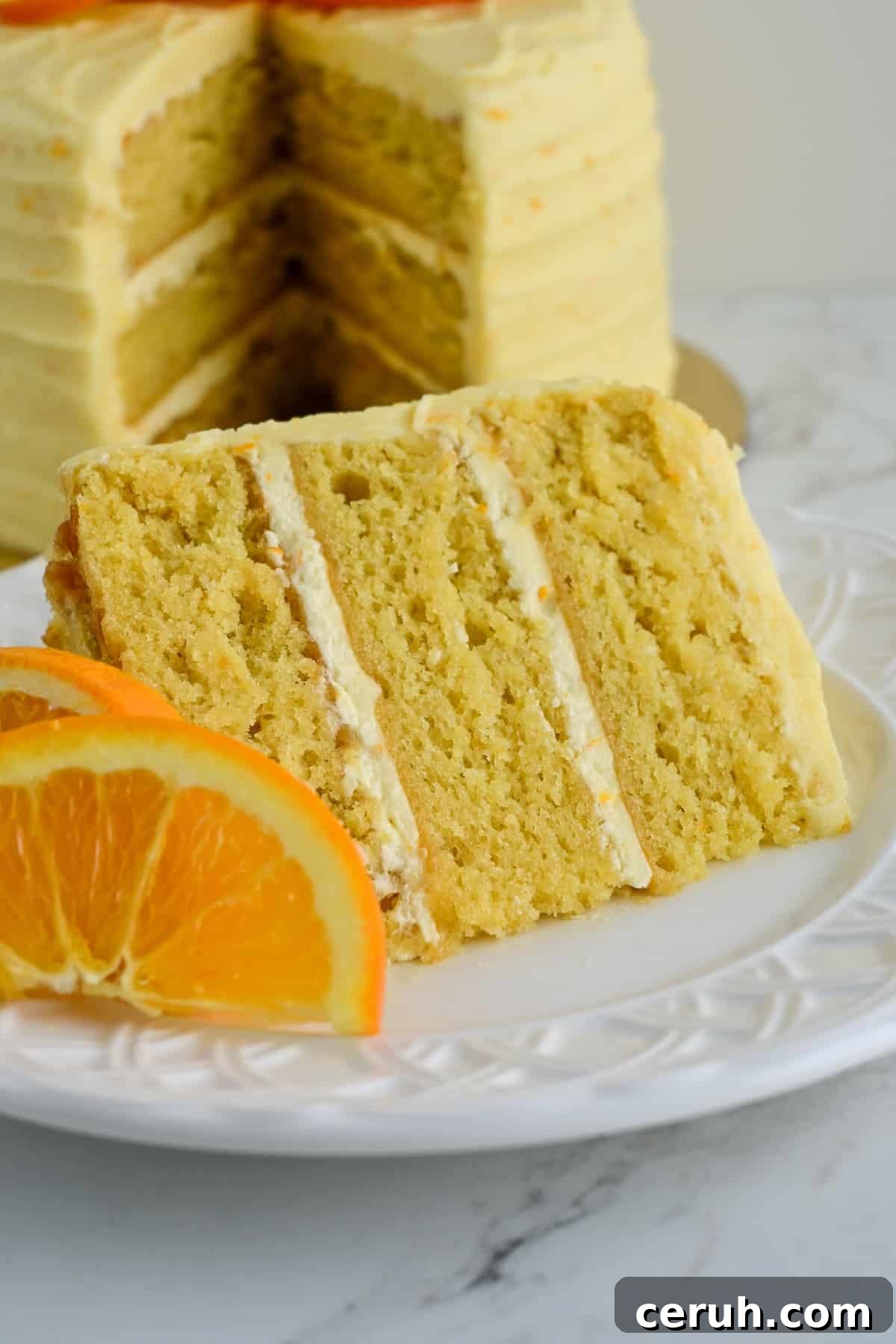 serving of orange almond cake recipe on a white plate with fresh orange slices next to it.