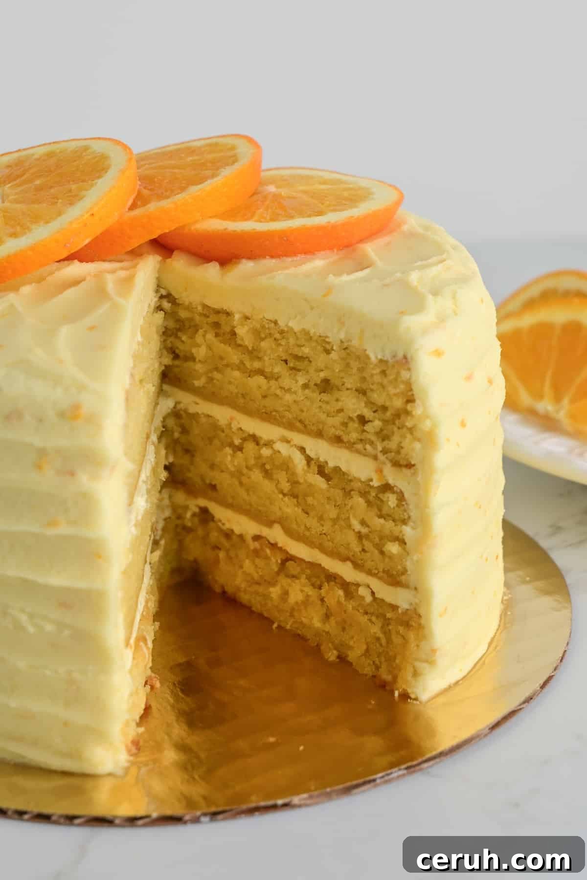 close up shot of a three layered orange almond cake to show the moist texture and flecks of orange zest in the frosting.