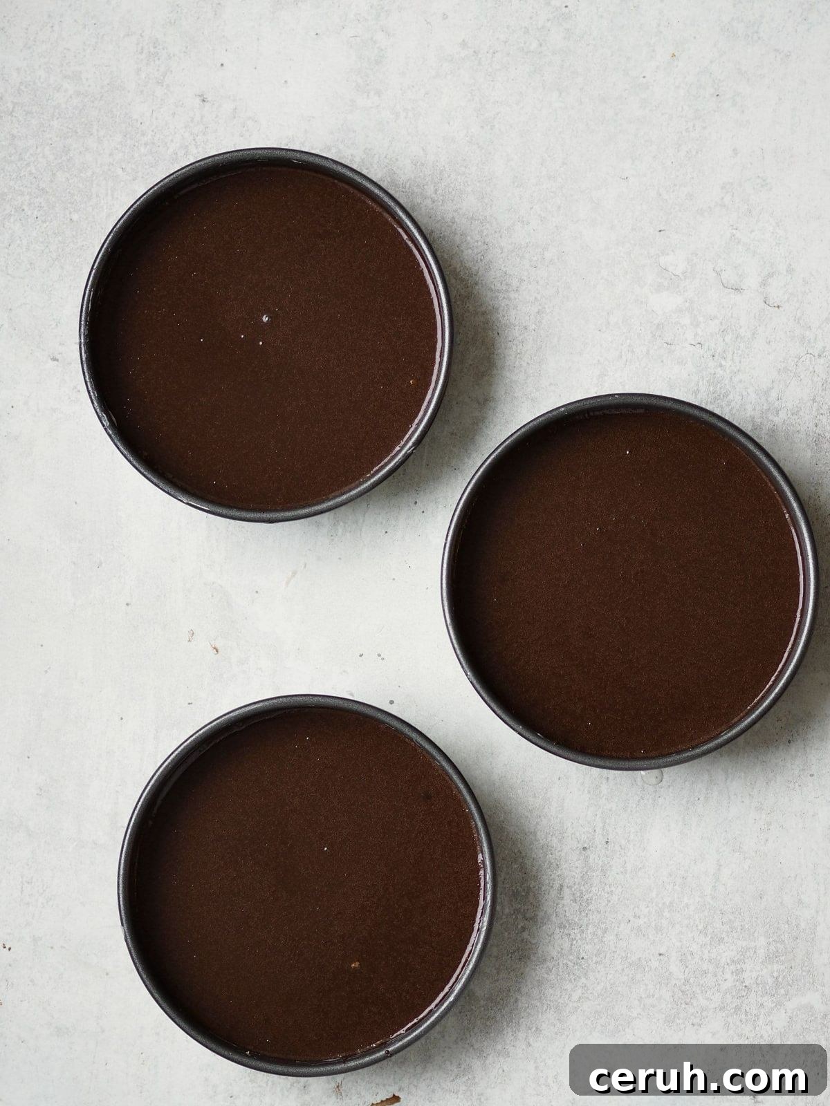 adding chocolate cake batter to the cake tin.