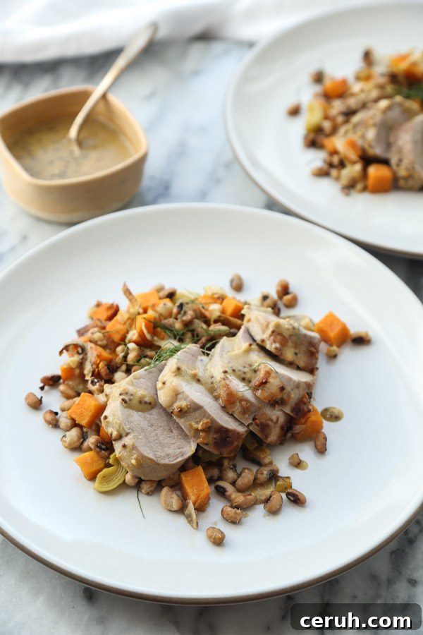 roasted pork tenderloin sliced on a plate with mustard sauce
