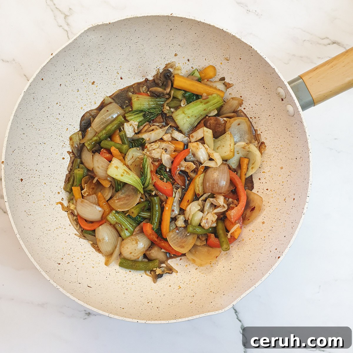 The steamed vegetbles in a wok mixed with the stirfry sauce.