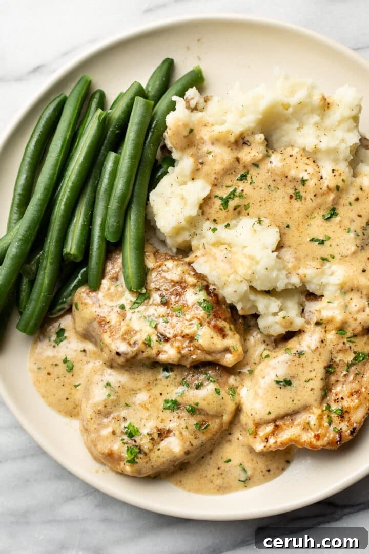 a plate with creamy pork tenderloin, mashed potatoes, and green beans