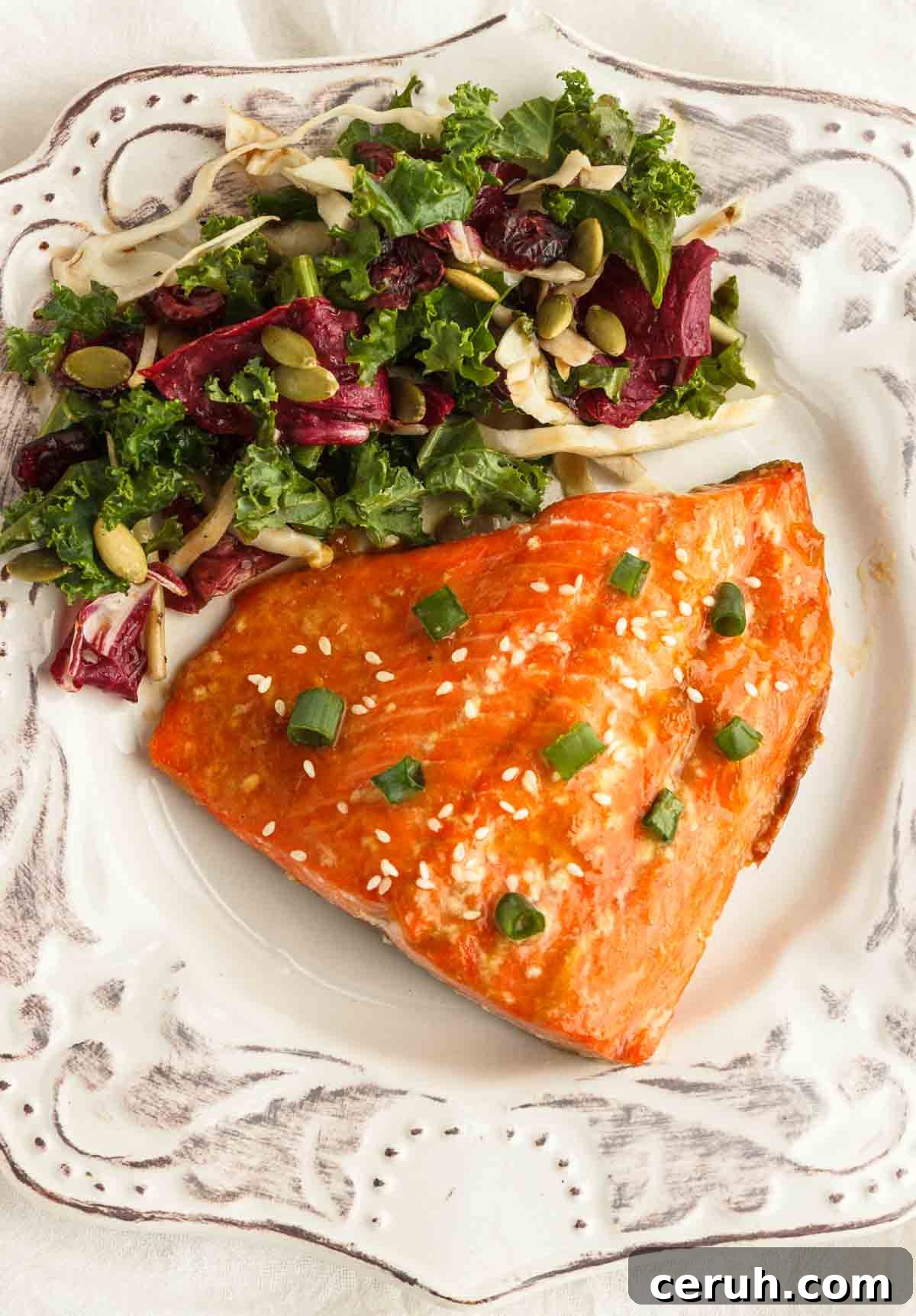 Apricot glazed salmon served with a salad on a white plate.