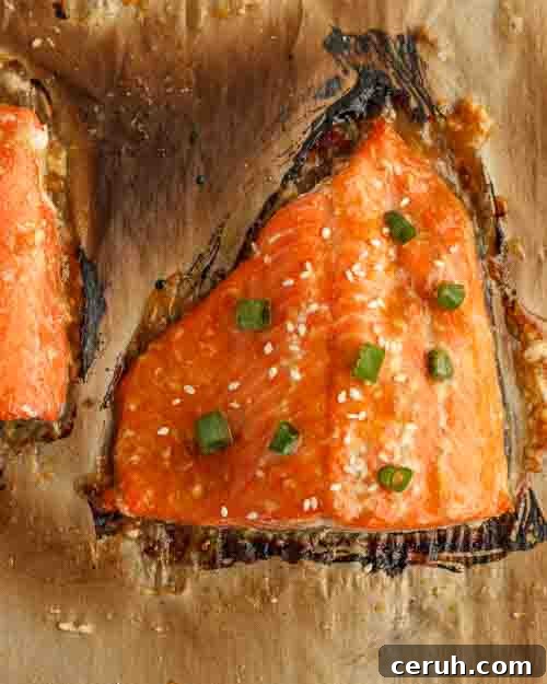 Garnishing baked apricot glazed salmon with scallions and sesame seeds.