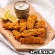 Keto air fryer fish sticks with lemon wedge.