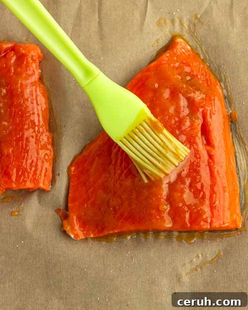 Brushing apricot glaze onto salmon fillets.