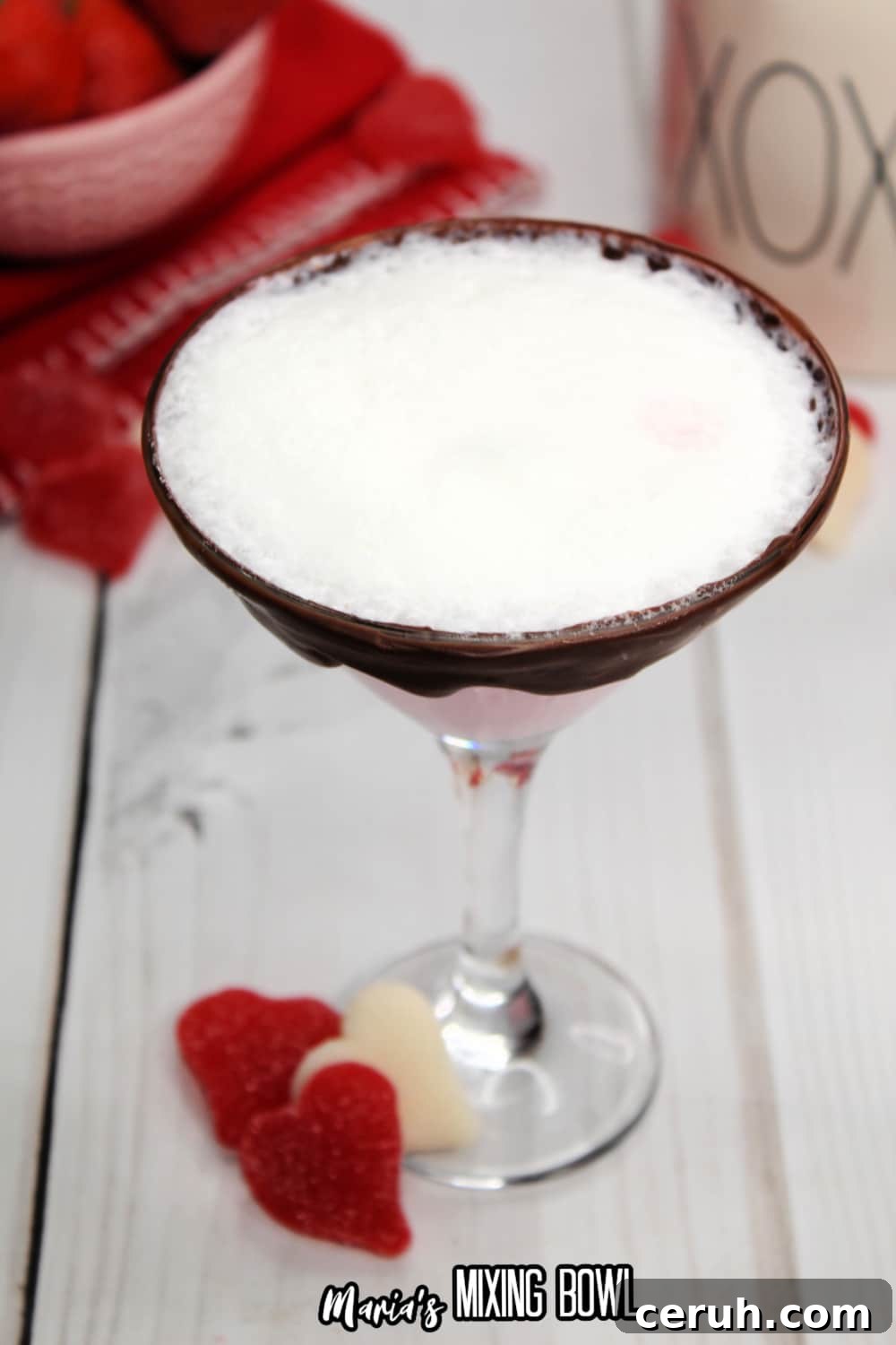 glass of strawberries and cream martini with a bowl of strawberries in the background