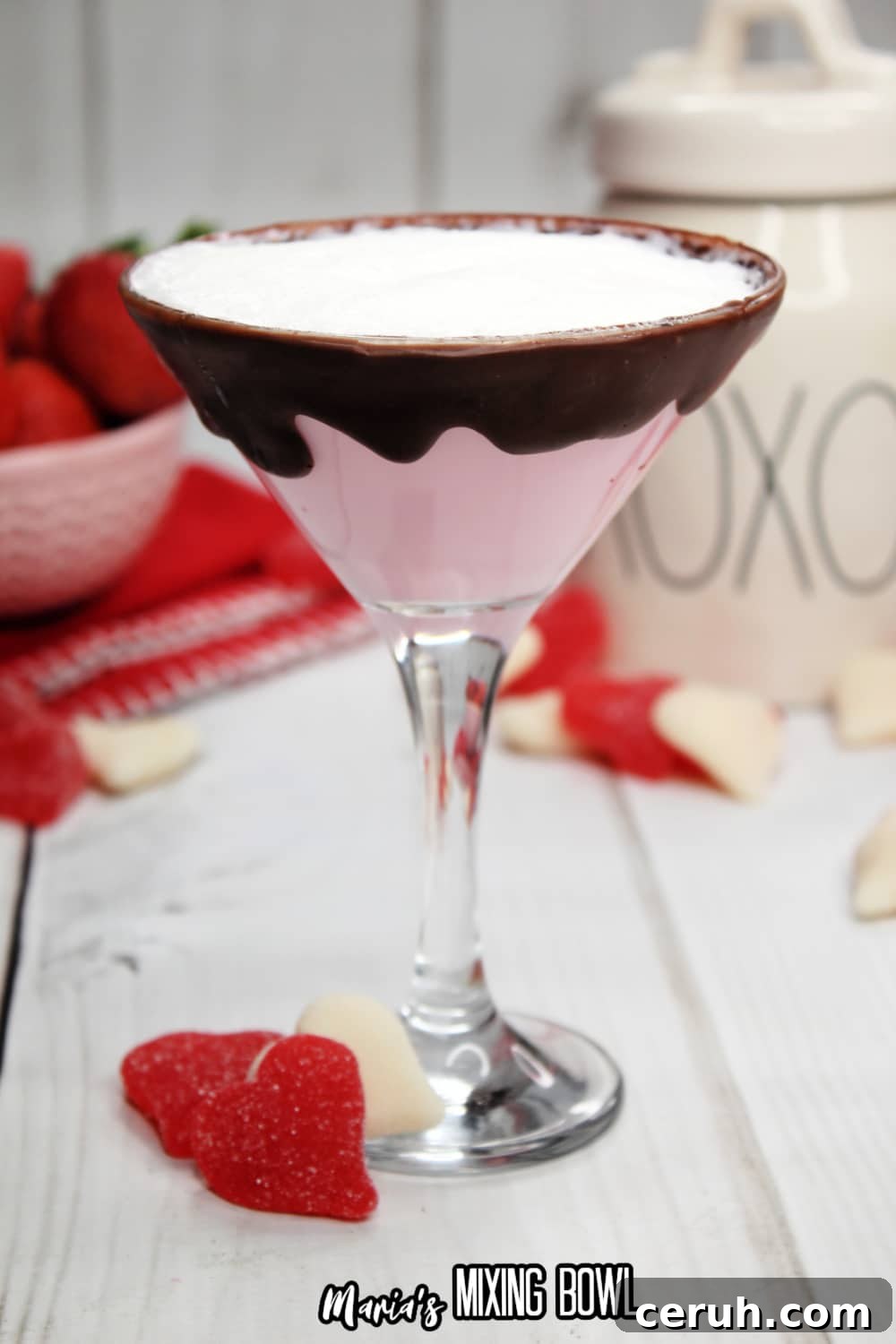 glass of strawberries and cream martini with a bowl of strawberries in the background