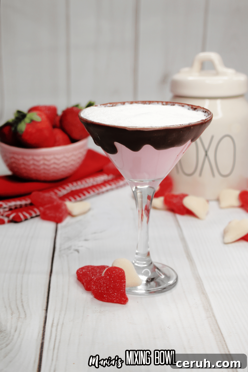 glass of strawberries and cream martini with a bowl of strawberries in the background