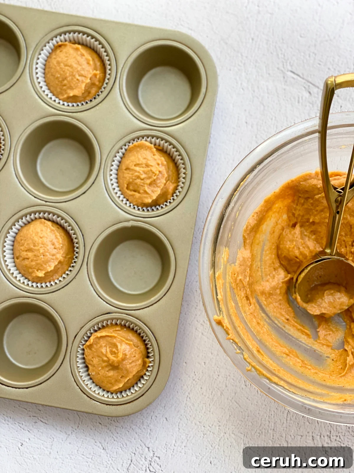 a bowl of pumpkin protein muffin batter with the muffin tin to the side.