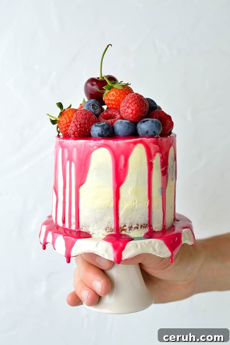 Mini white chocolate berry drip cake - delicious, moist vanilla cake with whipped white chocolate gananche, pink white chocolate drip and fresh berries; serves just 2-4 people!